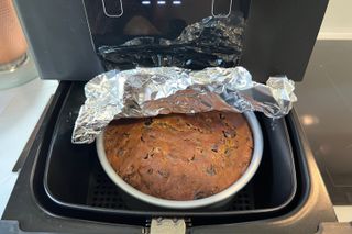 Step-by-step photo of a Christmas cake being baked in an air fryer - step 3, adding tin foil to the cake in the air fryer