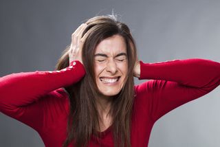 A woman covers her ears