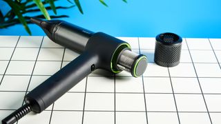 the heist 3.0 men's hair dryer in black with a bright green ring and magnetic attachment photographed against a blue background