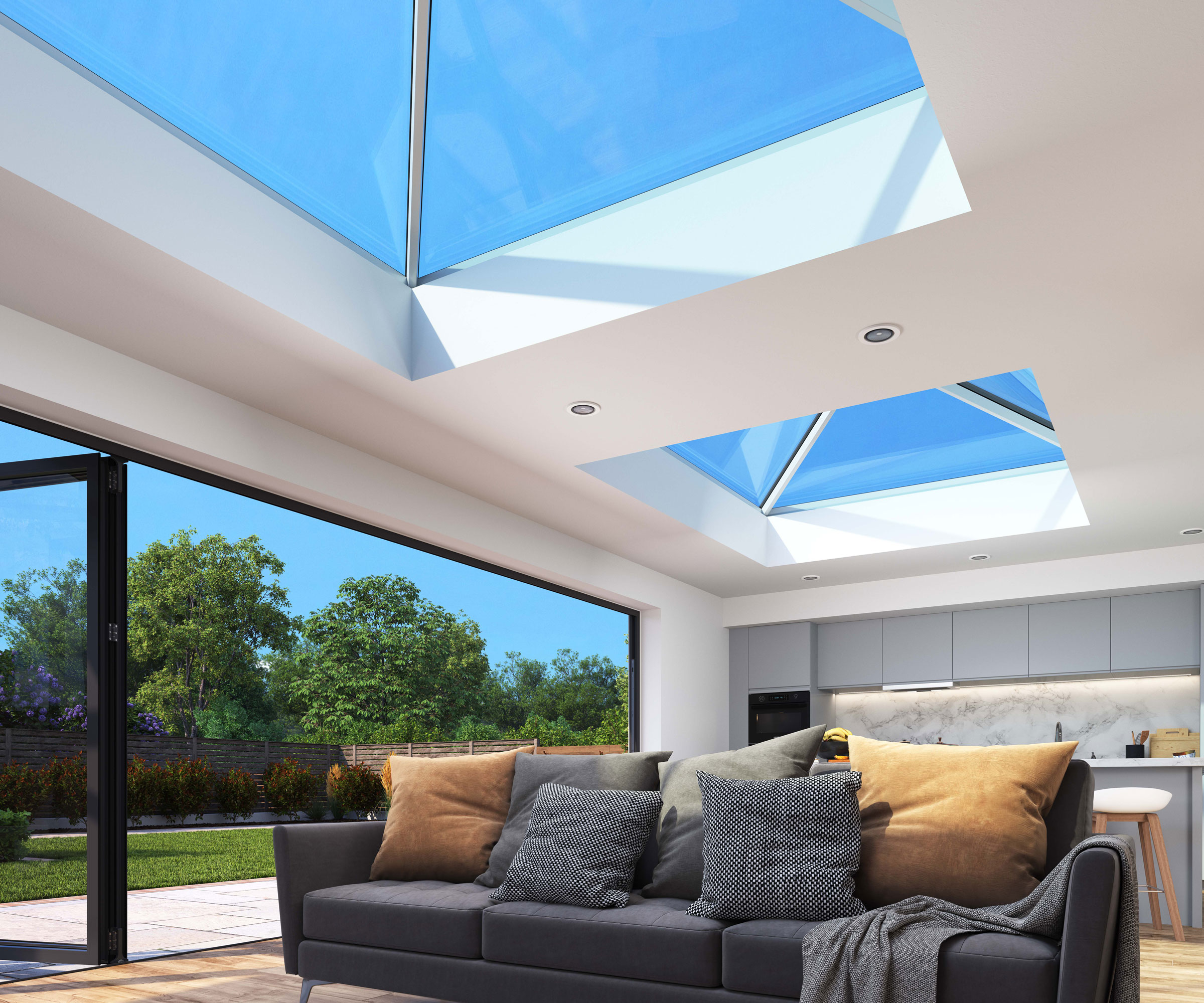 Large open plan living area with three seater sofa in foreground and a large expanse of Korniche bifold doors and two Korniche roof lanterns letting in lots of light