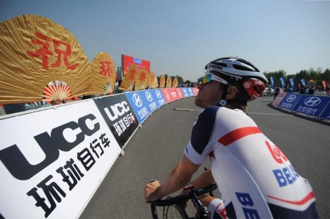 A cyclist of Lotto-Belisol team watches a performance as he prepares for the start of the first stage of the 2013 Tour of Beijing