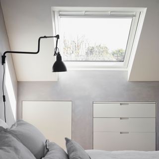 White painted bedroom, bed with grey bedding, black lamp