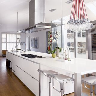 white kitchen with white dinning table and silver kitchen chimney