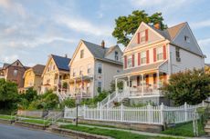 A photograph of a residential street lined with sunlit homes on a summer day in Tarrytown, New York, part of Rep. Mike Lawler's district.