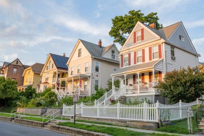 A photograph of a residential street lined with sunlit homes on a summer day in Tarrytown, New York, part of Rep. Mike Lawler's district.