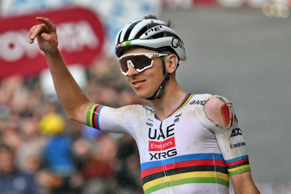 Tadej Pogacar (UAE Team Emirates) holds up one arm in celebration after winning Strade Bianche, covered in dust with his left shoulder torn up from an earlier crash