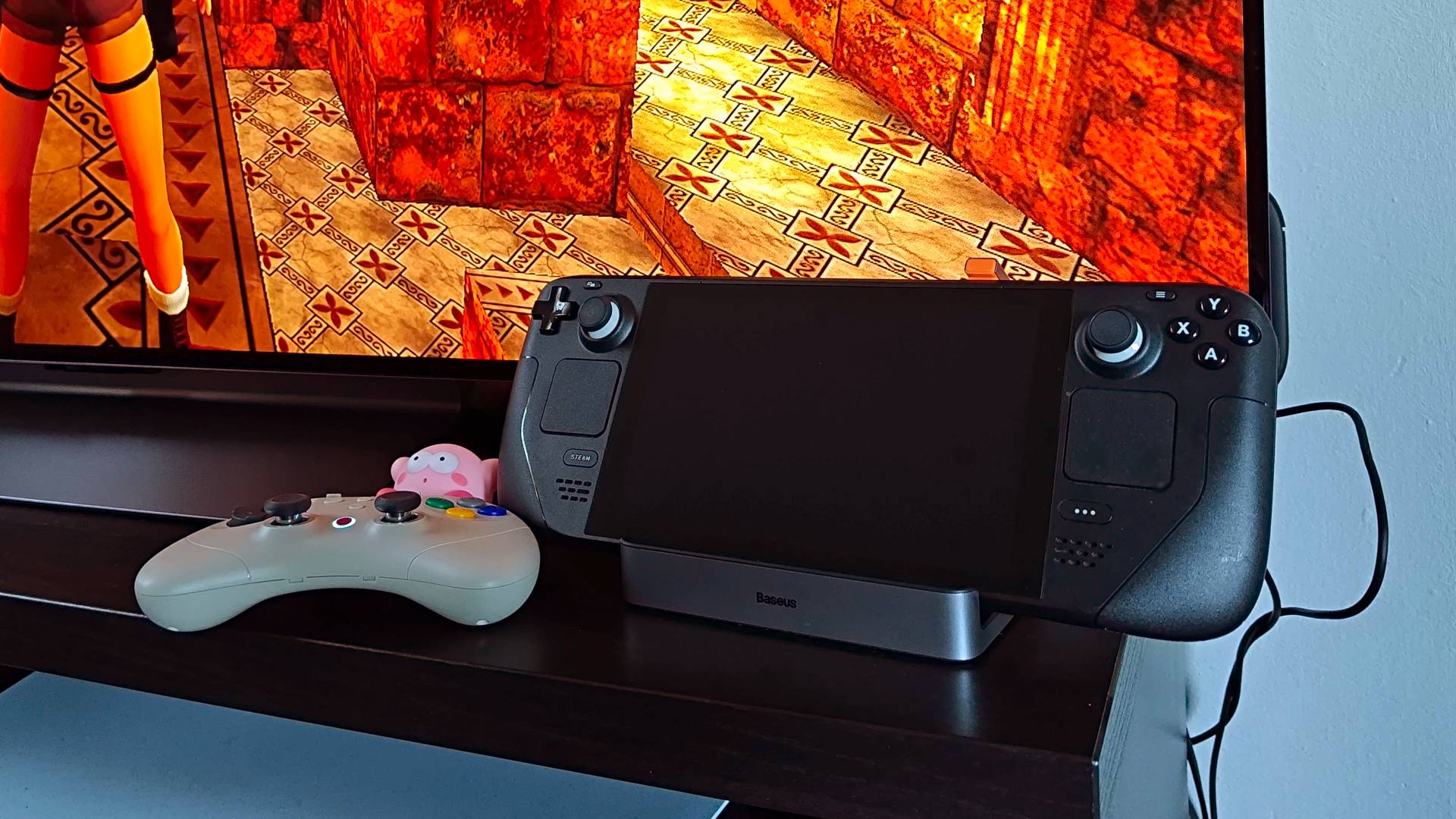 Steam Deck LCD model hooked up to Baseus docking station next to Gulikit Elves 2 Pro controller with LG OLED TV in backdrop.