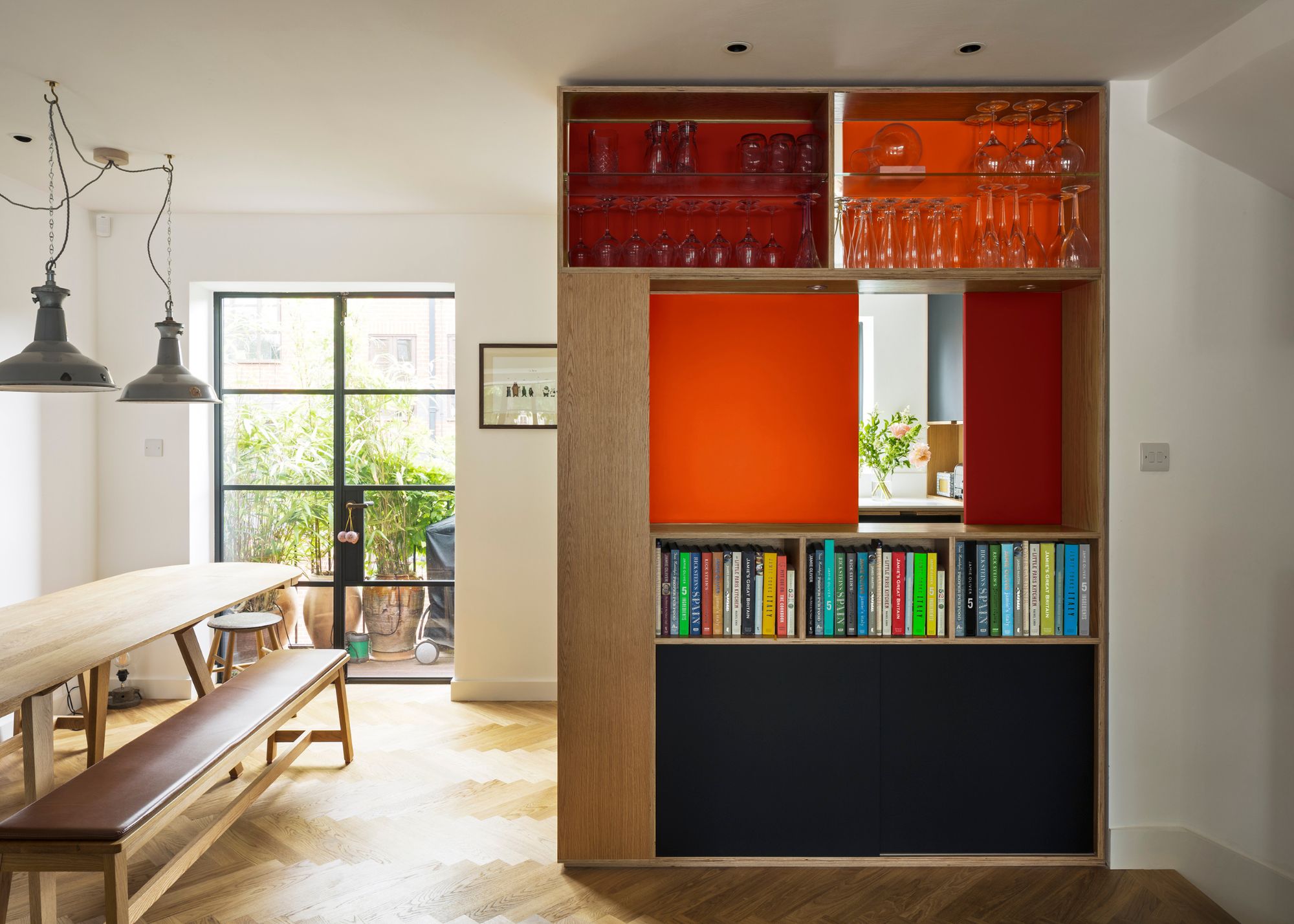 A ktichen in wood, with wooden floor, and a red sliding door