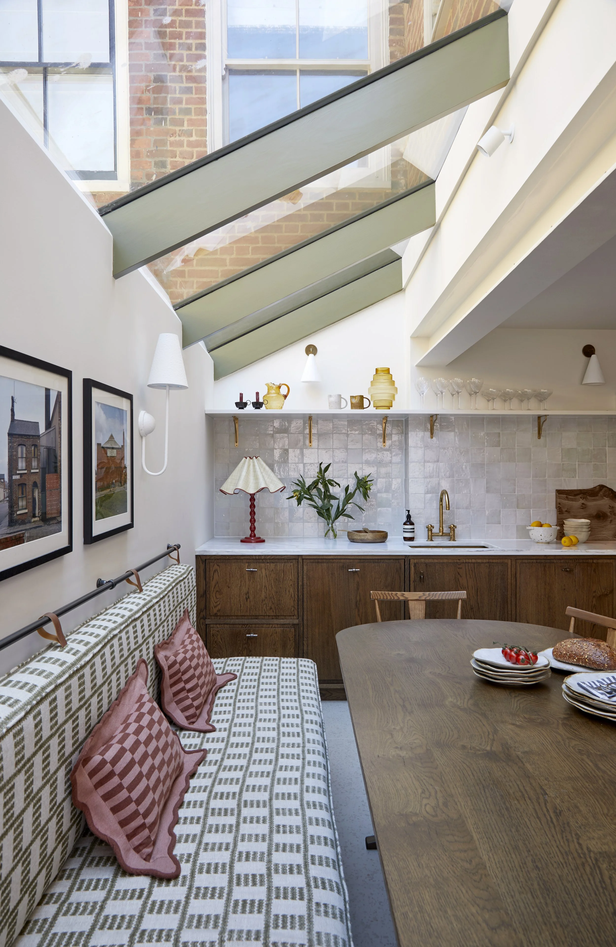 Airy kitchen with warm-wood cabinetry, zellige tiles and geometric-print banquette seating