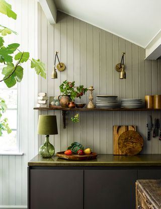 Green kitchen with brass wall lights