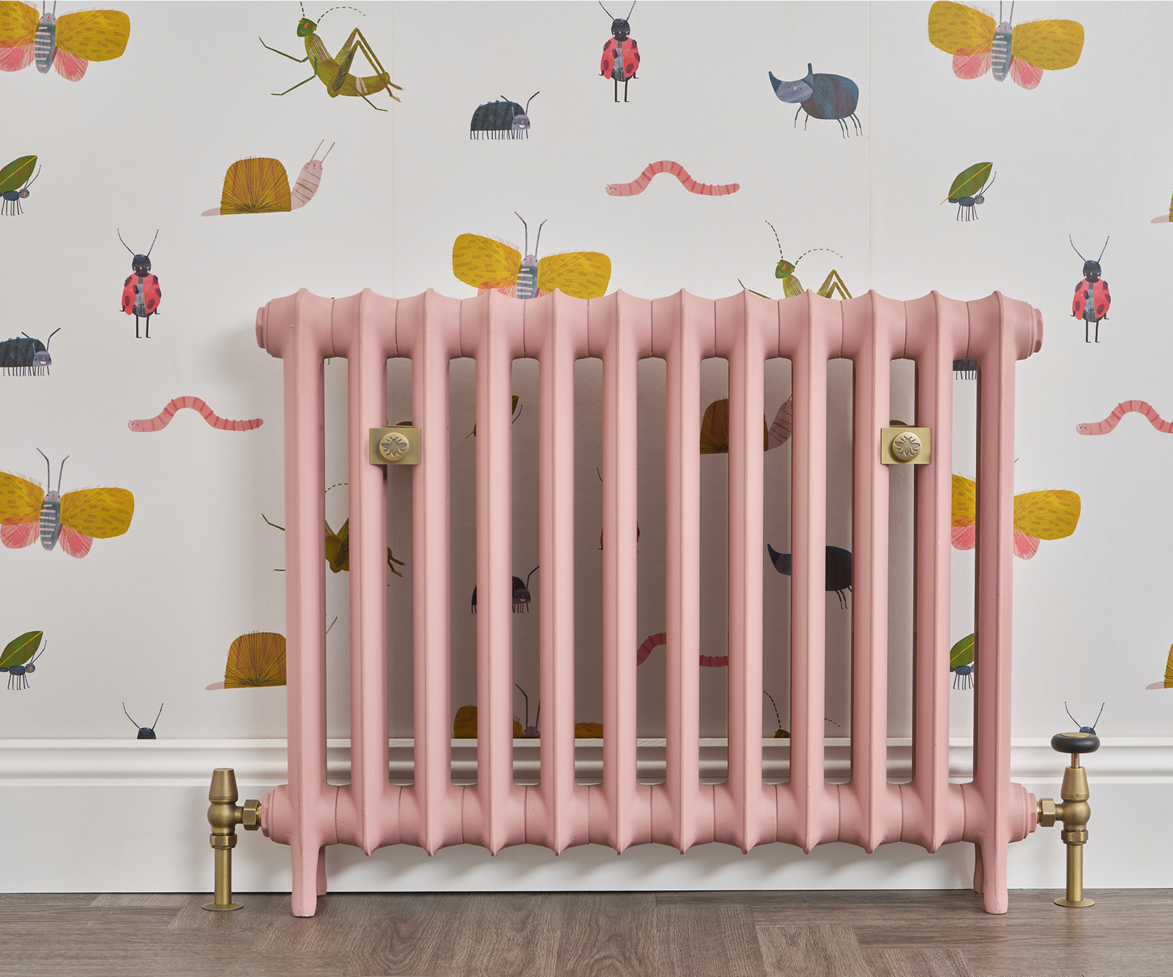 pink cast iron radiator on wall with nature themed children&#039;s wallpaper