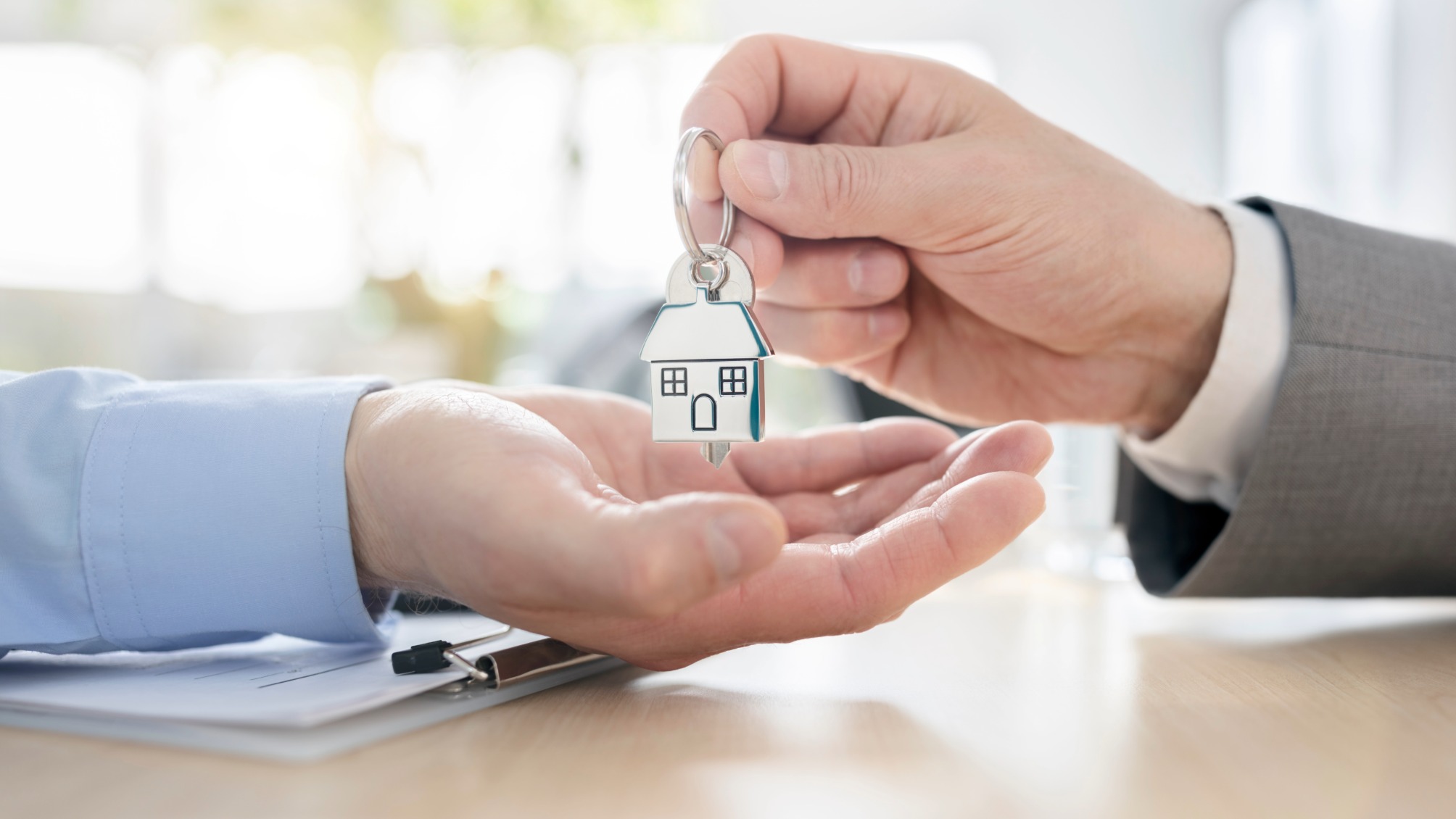 Close up of hands exchanging house shaped keychain in an office