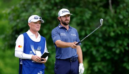 Cameron Young speaks to his caddie as he lines up a shot