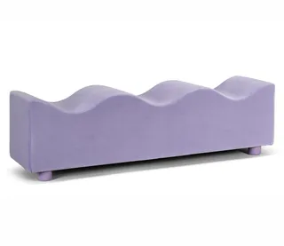 A lilla-colored, wavy sofa in velvet stands against a white background.