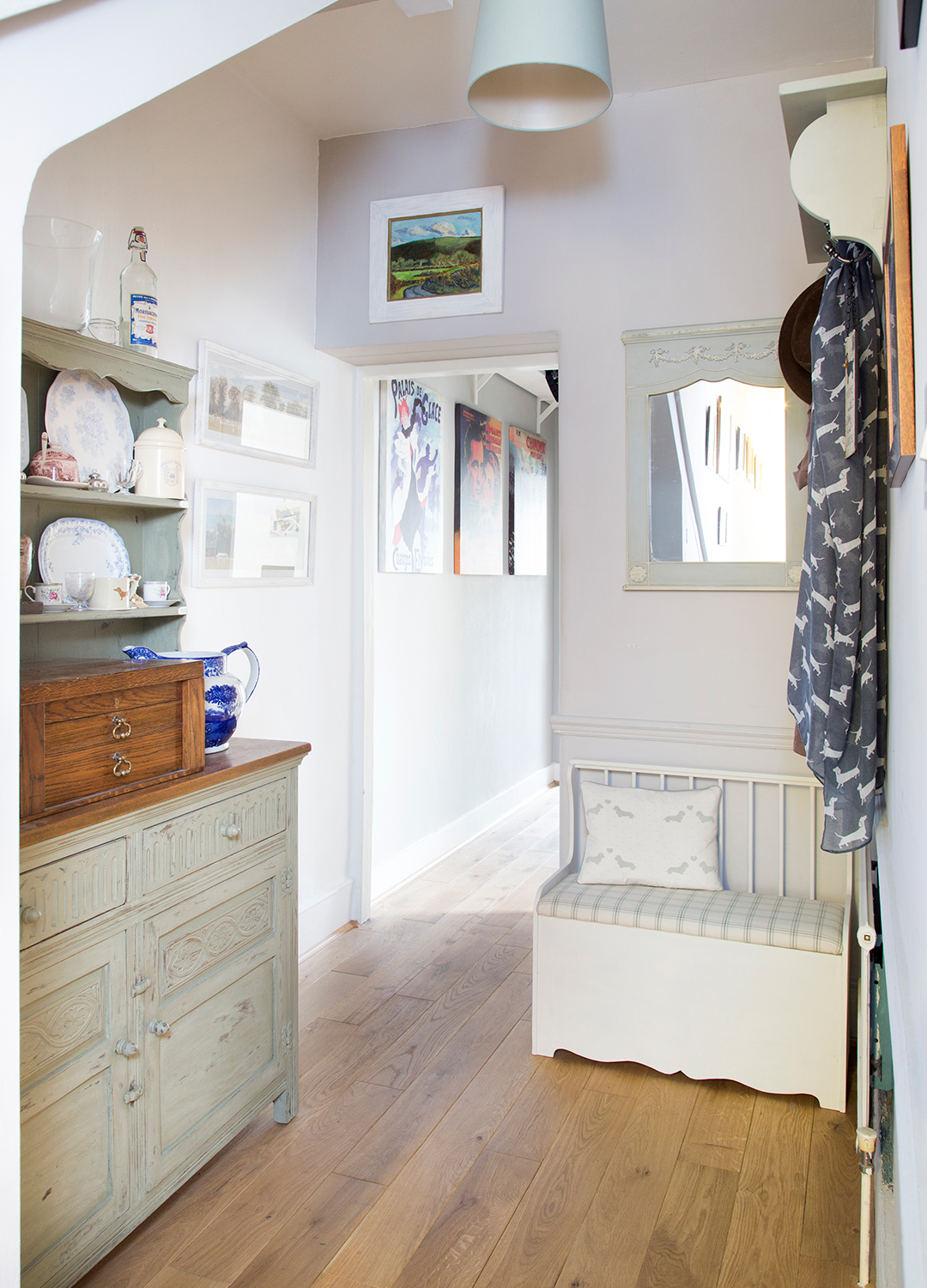 White hallway with a dresser and storage bench that leads through to a kitchen to support the idea of decluttering zones