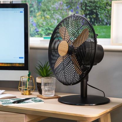 russell hobbs scandi wood effect desk fan on a desk with a computer