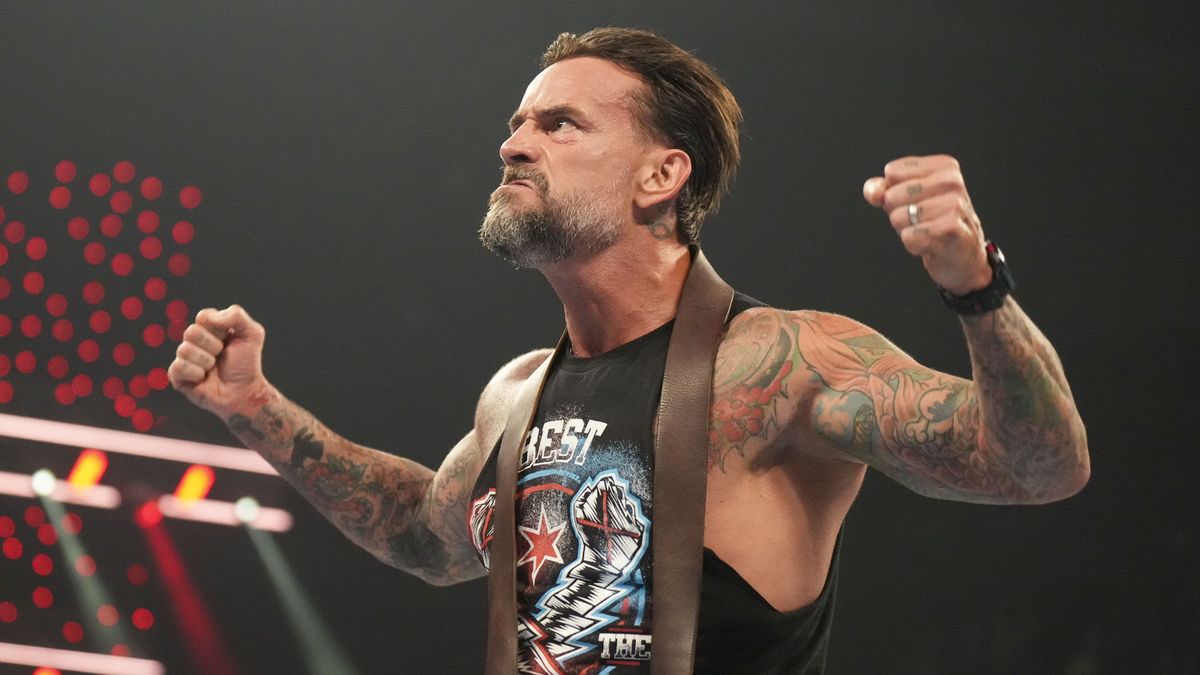 WWE wrestler CM Punk, wearing a black muscle vest, flexes his muscles to the crowd ahead of WWE Bad Blood 2024 live stream