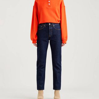 dark indigo Levi 501 straight legged jeans on a model worn with orange sweater
