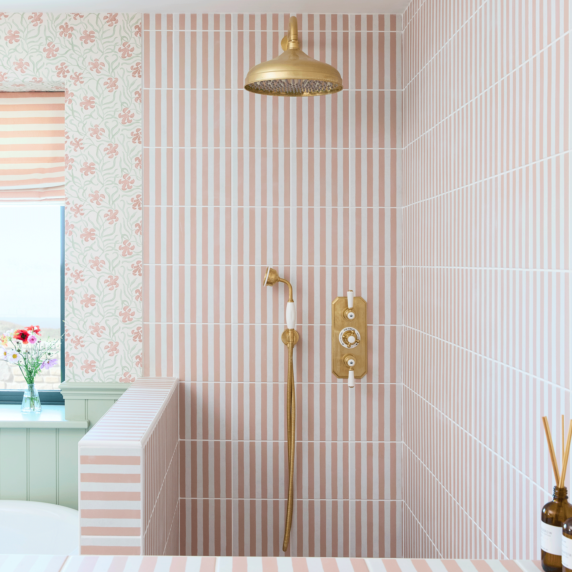 Bathroom with green wall panelling, floral wallpaper, pink and white stripe tiles in shower enclosure