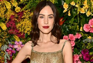 Alexa Chung wearing a gold mesh dress with black tights to the British Vogue and Tiffany & Co. party during London Fashion Week.