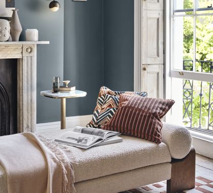 A living room painted blue with a boucle chaise longue