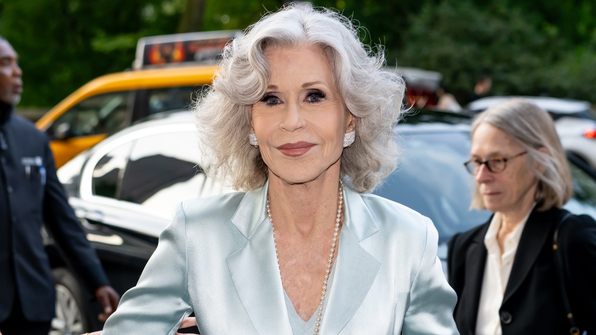 a paparazzi photos of a white woman with shoulder length gray hair in baby blue silk blazer