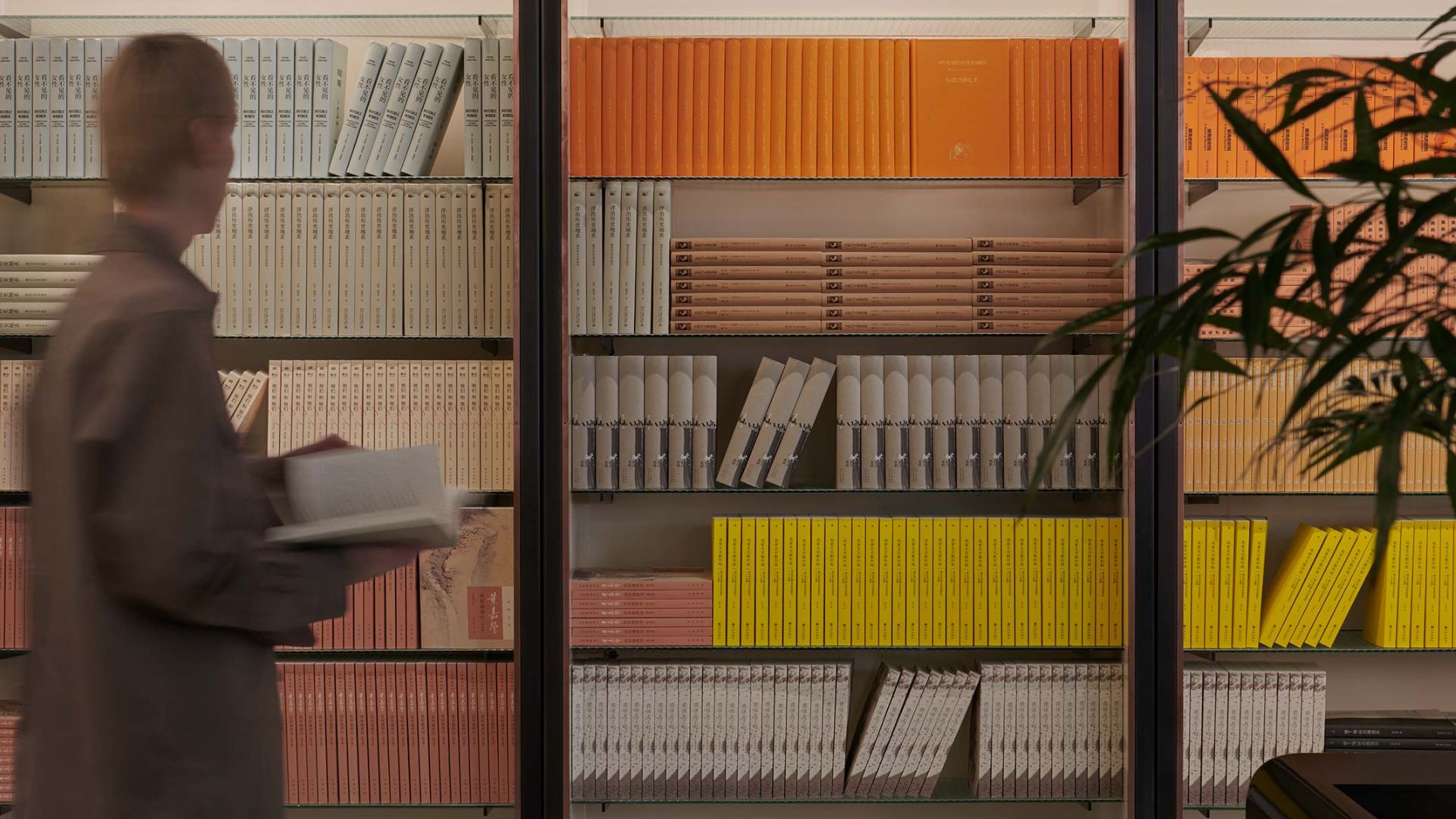 an image of a rack of books as part of Aesop's Queer Library with a person standing in front of it
