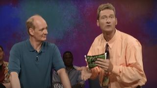 Colin looking at Ryan holding a bag of peas on Whose Line Is It Anyway?