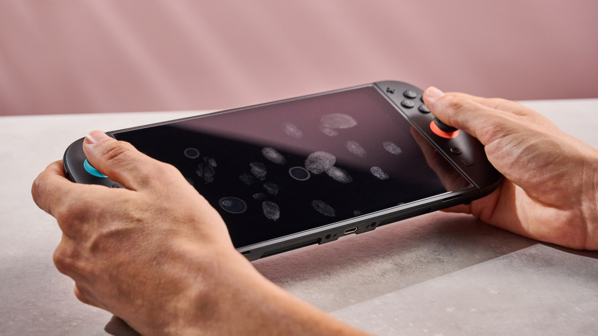 The Nintendo Switch 2 tilted at an angle to show the many fingerprints that have shown up on the Snakebyte Starter Kit S2 during application.
