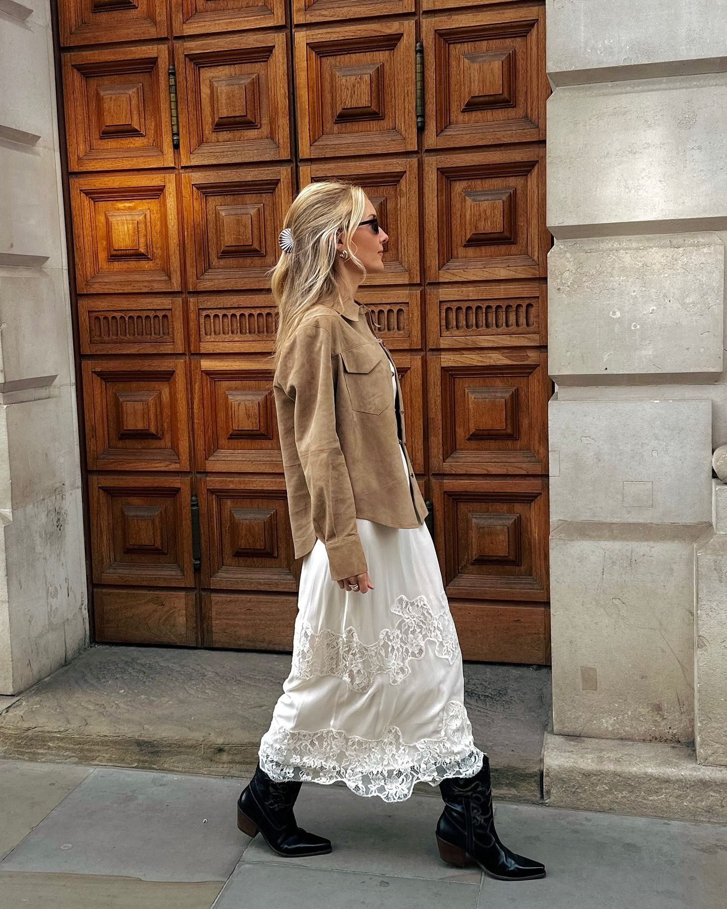 Chloe wears a suede coat, lace-trim skirt, and black cowboy boots.