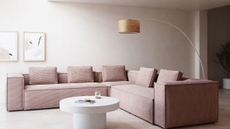 pink corduroy couch in a muted living room with a white coffee table and an arched floor lamp