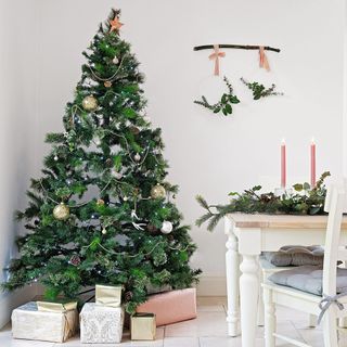 Decorated real Christmas tree in furnished white themed dining room