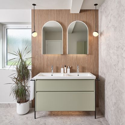 a double basin vanity unit with double mirrors and ceiling hung pendant lights