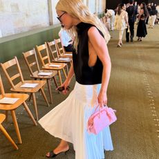 Stephanie Broek wearing a white pleated skirt and pink bag.