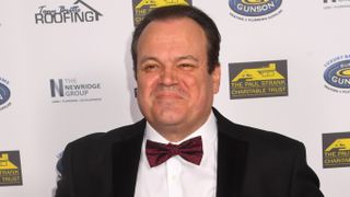 Shaun Williamson at a press event wearing a suit and bow tie