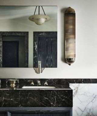 Art Deco style bathroom with marble sink and tiles, mirror, glass pendant light and silver taps