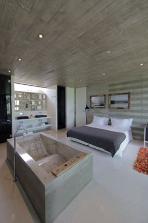 Interior view of the eco-resort Rio de Prado room, with a large bed and a marble bathtub, in gray and beige tones.