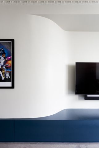 bedroom with movie poster on left, tv on right, low media storage in blue, stone floor