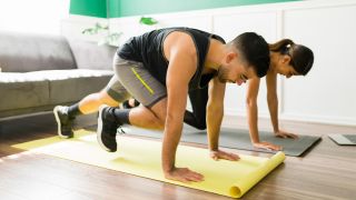 Woman and man perform the mountain climber exercise in their home