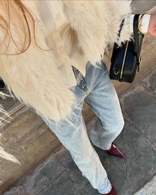 woman wearing white fur jacket and baggy jeans with stiletto heels