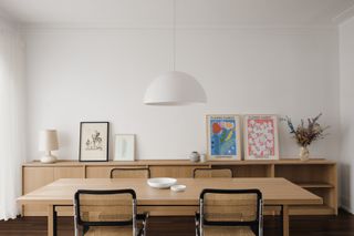 Simple white dining room with wooden table and chairs and minimalist art