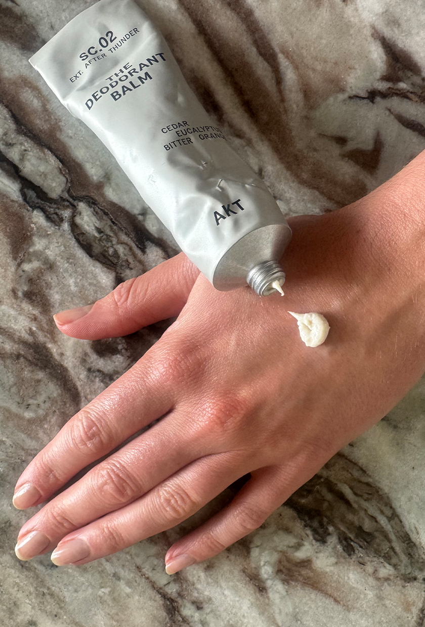 Squeezing out AKT The Deodorant Balm in After Thunder scent onto hand