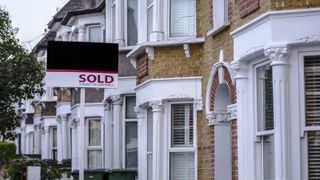 Mortgage valuation outside of brick town house with white bay windows and sold sign