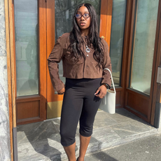 Nnenna Echem wearing a brown top and oval shaped glasses with a pendant necklace. 