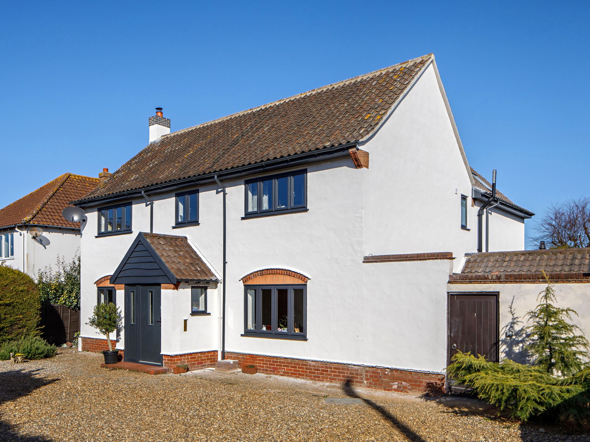 Rumah besar terpisah dengan plester putih dan jendela hitam