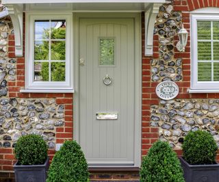 sage green composite slatted front door on brick house with white windows