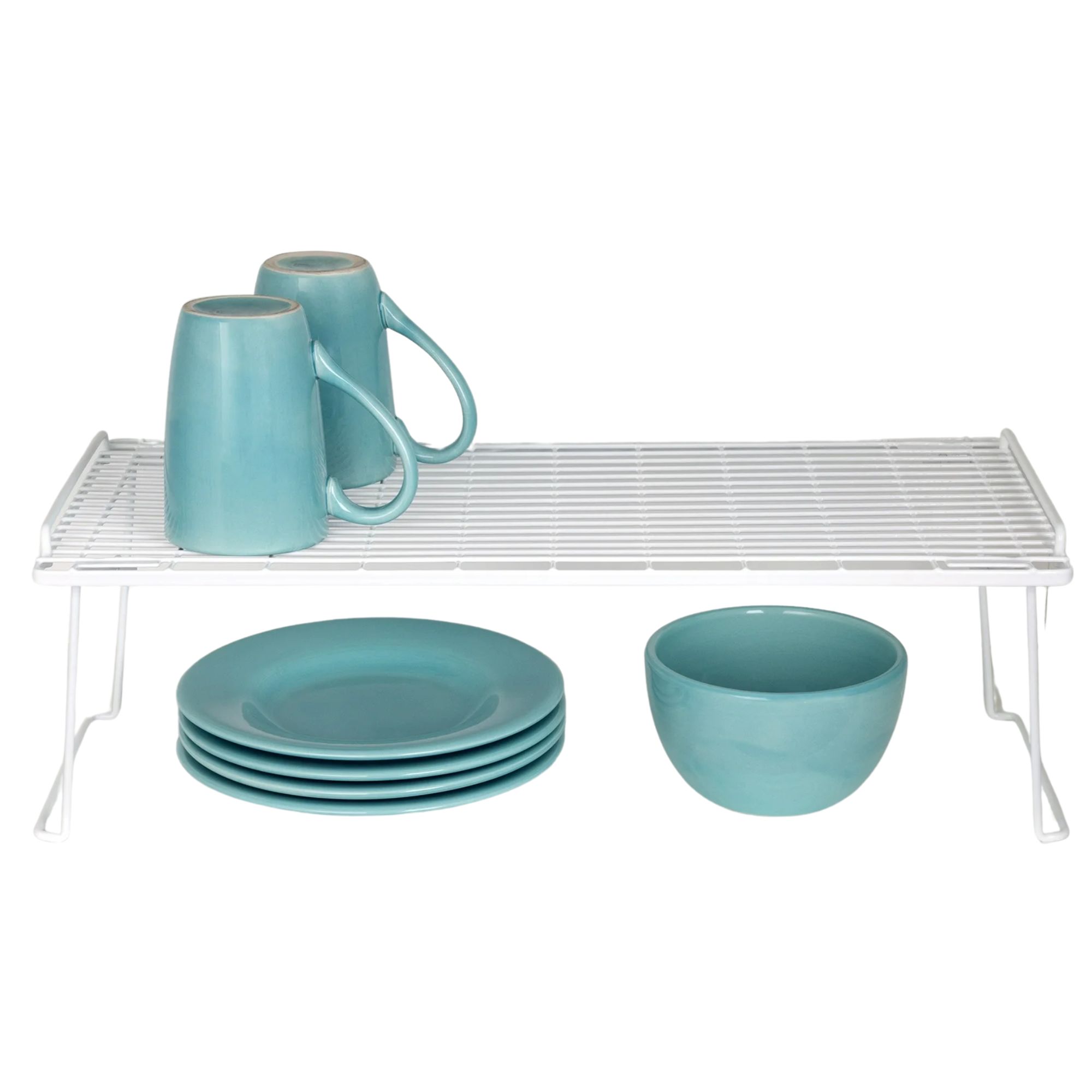 A white shelf riser with blue mugs upside down on top, and a stack of blue plates next to a blue bowl below
