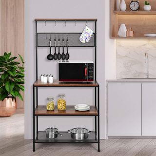 Tiered black metal rack with dark wooden shelves stacked with pots pans food containers microwave and utensils