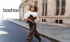 Boohoo logo placed over an image of a woman in a nice outfit posing in a street