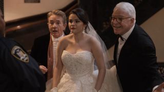 A screenshot from Only Murders in the Building of Selena Gomez in a wedding dress, with Steve Martin to the right of her smiling and Martin Short behind her looking a bit shocked. 